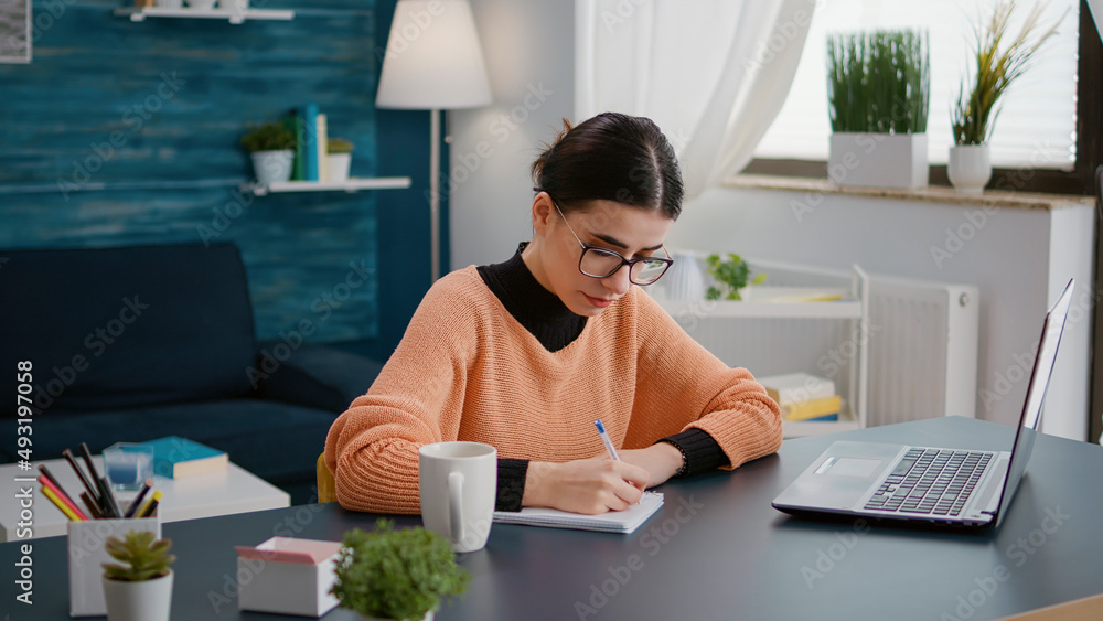 Poster portrait of young student taking notes on textbook in online class on laptop, attending remote cours