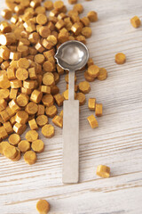 Sealing wax spoon and yellow gold sealing wax granules or beads a lot on wooden background....