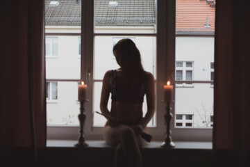 Fototapeta na wymiar Domina Frau in Schwarz Leder zuhause in Kerzen licht und Peitsche und Maske