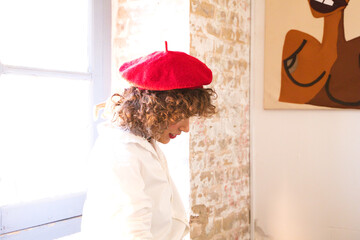 young, beautiful, enterprising woman. Dedicated to the art of painting and fashion design, she wears a red beret on her head and is posing for the photo. Enterprising woman concept