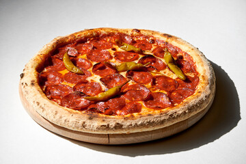 Crispy pizza with salami pepperoni, jalape?o peppers on a gray background.