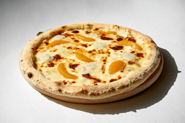 Crispy 4-cheese pizza with peaches on a gray background.