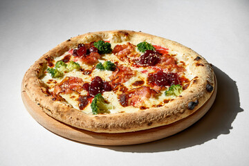 Crispy pizza with broccoli and bacon on a gray background.