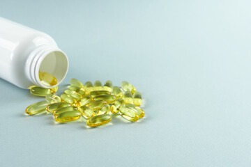 Capsules with fish oil, on a gray background with a white bottle, fish oil, dietary supplement with omega-3, heart care.