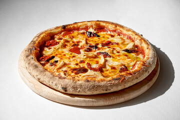 Crispy pizza with chicken and sun-dried tomatoes on a gray background.