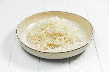 Rice porridge in a plate on a white wooden background.