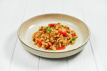 Rice and vegetables wok in a plate on a white wooden background.