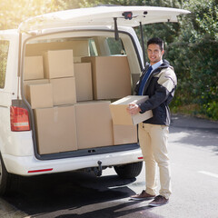 Striving for service excellence. Portrait of a friendly delivery man unloading cardboard boxes from his van.