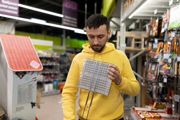 a customer in a hardware store chooses a new grate for grilling and barbecue