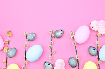 Willow branches with buds, Easter bunnies and colored eggs on a pink background. Easter composition, top view, copy space