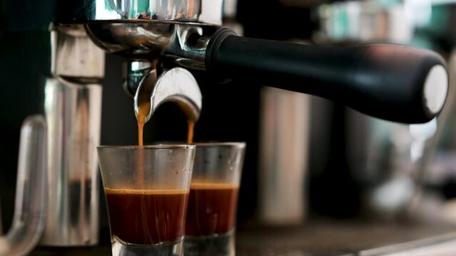 4K : Pouring coffee stream from professional machine in cup. Barista man making espresso shot by using filter holder. Flowing fresh ground coffee. Drinking roasted black coffee.