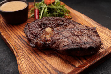 Grilled steak with sauce and herbs, on a wooden board