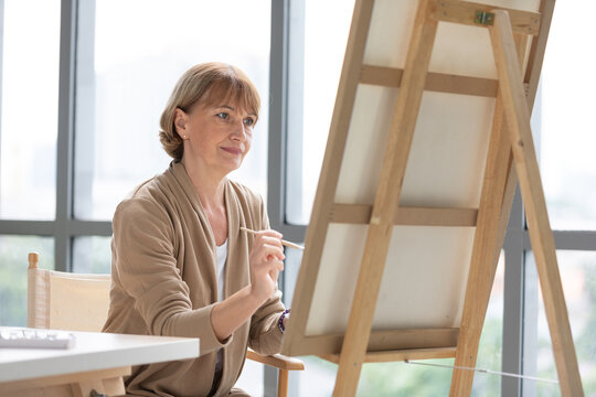 senior woman painting a picture from paintbrush in free time