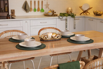 Table with dishware in beautiful kitchen decorated for Christmas. Interior design