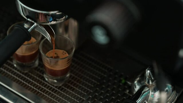4K : Pouring coffee stream from professional machine in cup. Barista man making espresso shot by using filter holder. Flowing fresh ground coffee. Drinking roasted black coffee.
