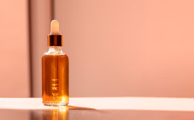 Fototapeta premium Cosmetic glass dropper bottle with oil, serum or fruit peeling in the sunlight. Natural beauty product presentation on natural background. Front view. Web banner. Mockup concept for cosmetic products