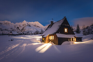 Mountain chalet in the Tatras during the blue hour. Winter mountain landscape with a view of the mountain ridges.