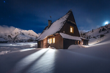 Mountain chalet in the Tatras during the blue hour. Winter mountain landscape with a view of the mountain ridges.