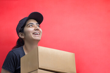 Smiling Young Delivery Woman Holding Cardboard Box Against Color Background