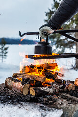 An old coffee pot on camp fire in winter in Lapland Finland. 