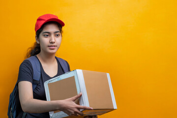 Young Delivery Woman Holding Cardboard Box Against Yellow Background