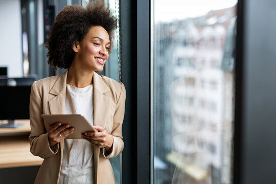 Portrait of young successful black woman working with tablet in office