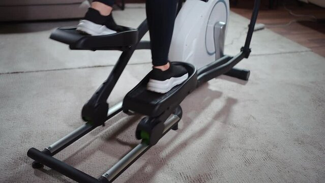 close up female legs running on elliptical orbitrek machine in fitness gym