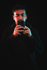 Junger Mann mit Mobiltelefon. schwarzer Hintergrund. Handyfoto