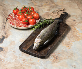 Raw trout with rosemary, prosciutto parma and tomatoes on a wooden vintage background, healthy...