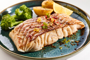Tasty grilled fish on plate on white table