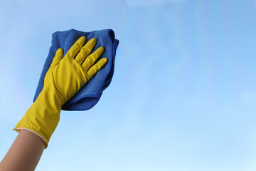Woman cleaning window glass with rag, closeup. Space for text