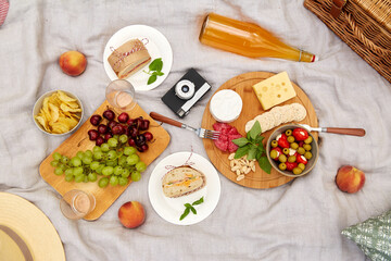 leisure, food and drinks concept - close up of snacks and camera on picnic blanket on blanket
