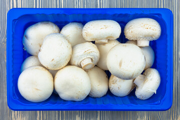 White champignon mushrooms on a wooden table.
