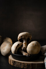 still life of mushrooms on wooden board pan and black background