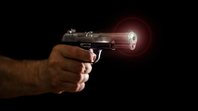 View of the muzzle of the pistol barrel with lens flare . Old russian semiautomatic pistol (Tokarev) held in hand on black background. 