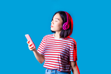 Young asiatic woman isolated listening music holding smartphone