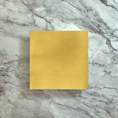 Yellow gold square on a bright gray marble background. Text space. Top view. Minimal style.