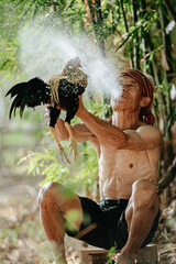 Asian senior man  blowing water to his fighting cock