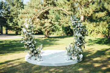 Very beautiful outside ceremony. classical wedding in forest. Metal arch with flowers.