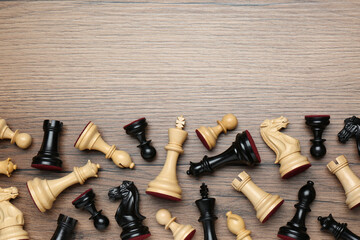 Many different chess pieces on wooden table, flat lay. Space for text