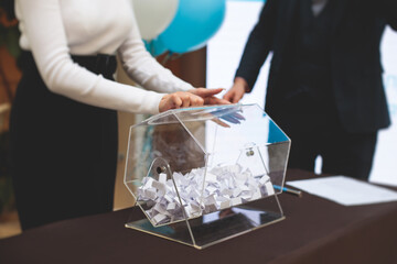 Process of prize drawings, extracting a winning numbers of lottery machine, raffle drum with bingo balls and winning tickets on event with a host and hands on lottery machine