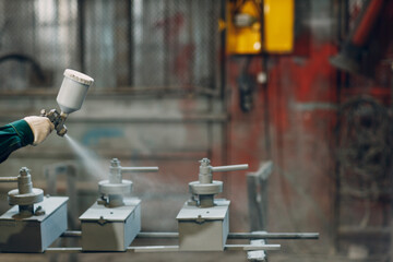 Powder primer coating of metal parts. Worker man in a protective suit sprays powder paint from gun...