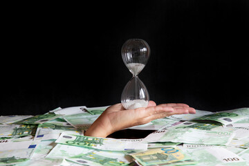 concept time is money, the hand that holds the hourglass climbs out of the pile of money