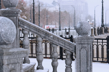 Balustrade of the rotunda under the snow. Gray granite exterior details during a snowfall. Fragment...