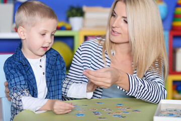 Fototapeta premium Portrait of mother and son collecting puzzle pieces