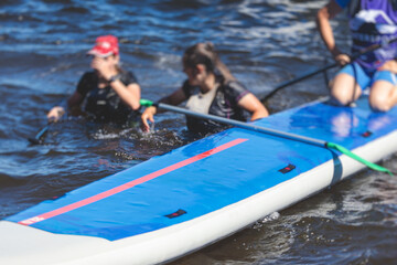 Group of young sup surfers fall from SUP stand up paddle board, women drowning, concept of fail...