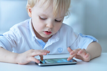 Portrait of boy with smartphone playing the game at home