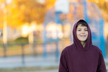 Smiling teen boy 14-16 year old wearing hoodie outdoors. Looking at camera. Teenager hood.