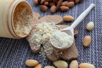 Close-up of almond kernels, peeled and not, almond flour in a wooden barrel on a napkin.