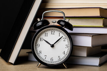 Naklejka premium Clock on the background of a stack of books
